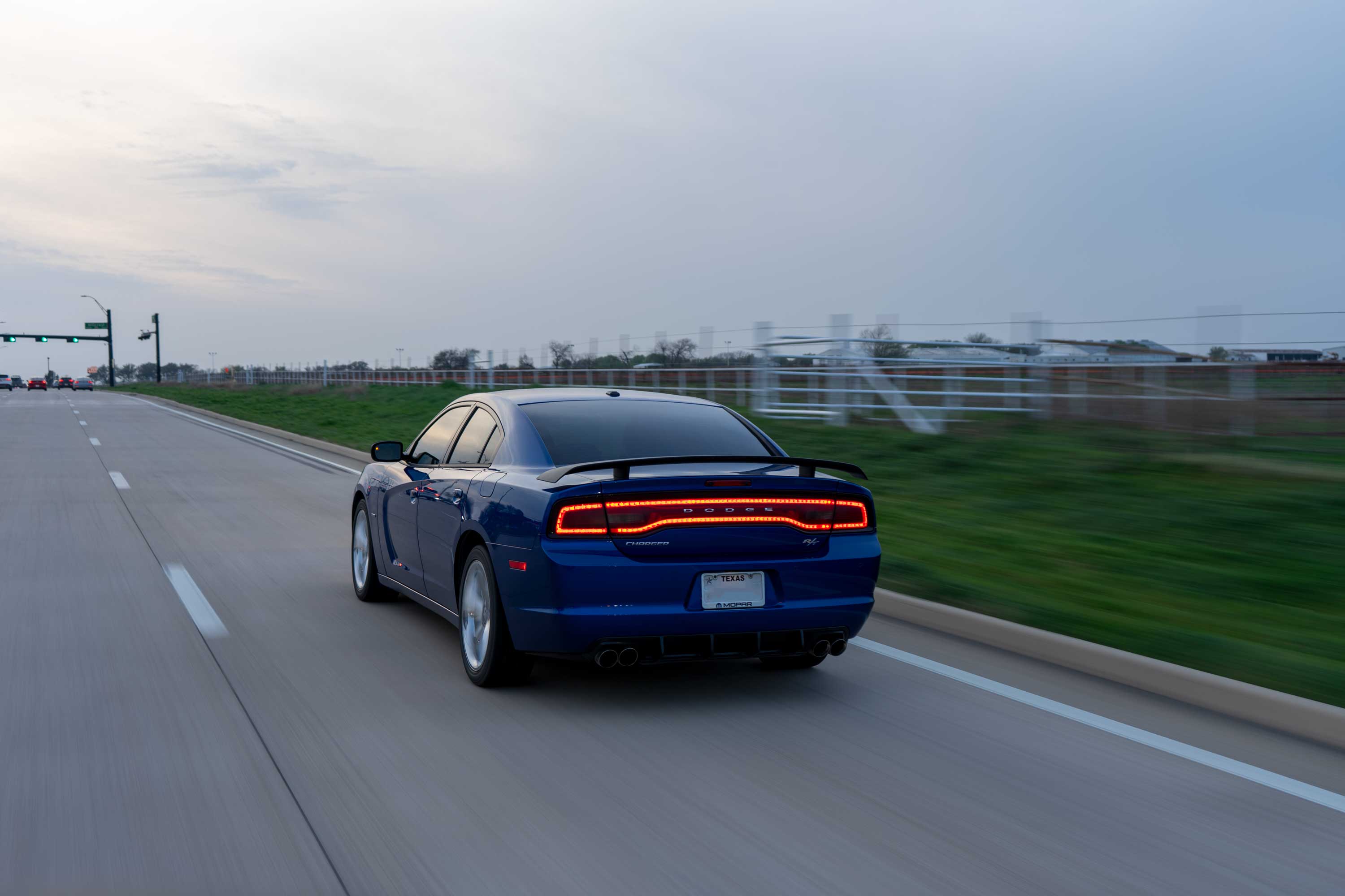 A blue dodge charger drives down a empty texas road.